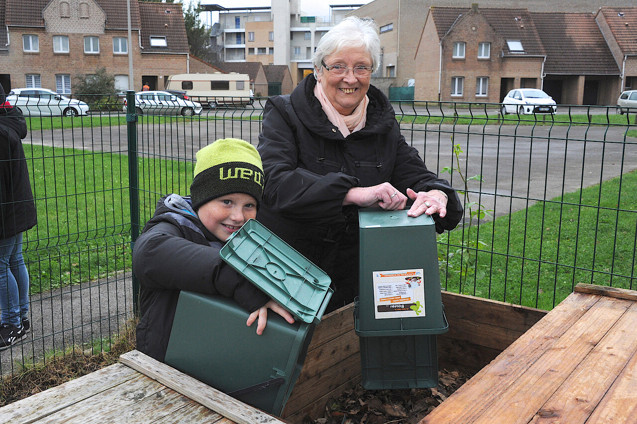 Un adulte et un enfant participe à l'espace de compostage collectif de leur quartier 